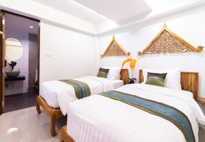 Habitación de hotel con dos camas, baño con lavamanos y paneles decorativos en la pared.