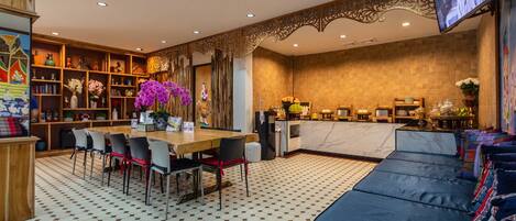 Un hall de hotel con zona de comedor, un sofá, un televisor y una encimera de cocina.
