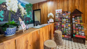 A wooden reception desk with a mural of an elephant and flowers, a plant, and a sign indicating a price of 100. - Anumat Premium Budget Hotel (Chiang Mai)