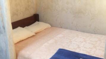 A small, single-bed room with a patterned wall and a blue object on the bed.