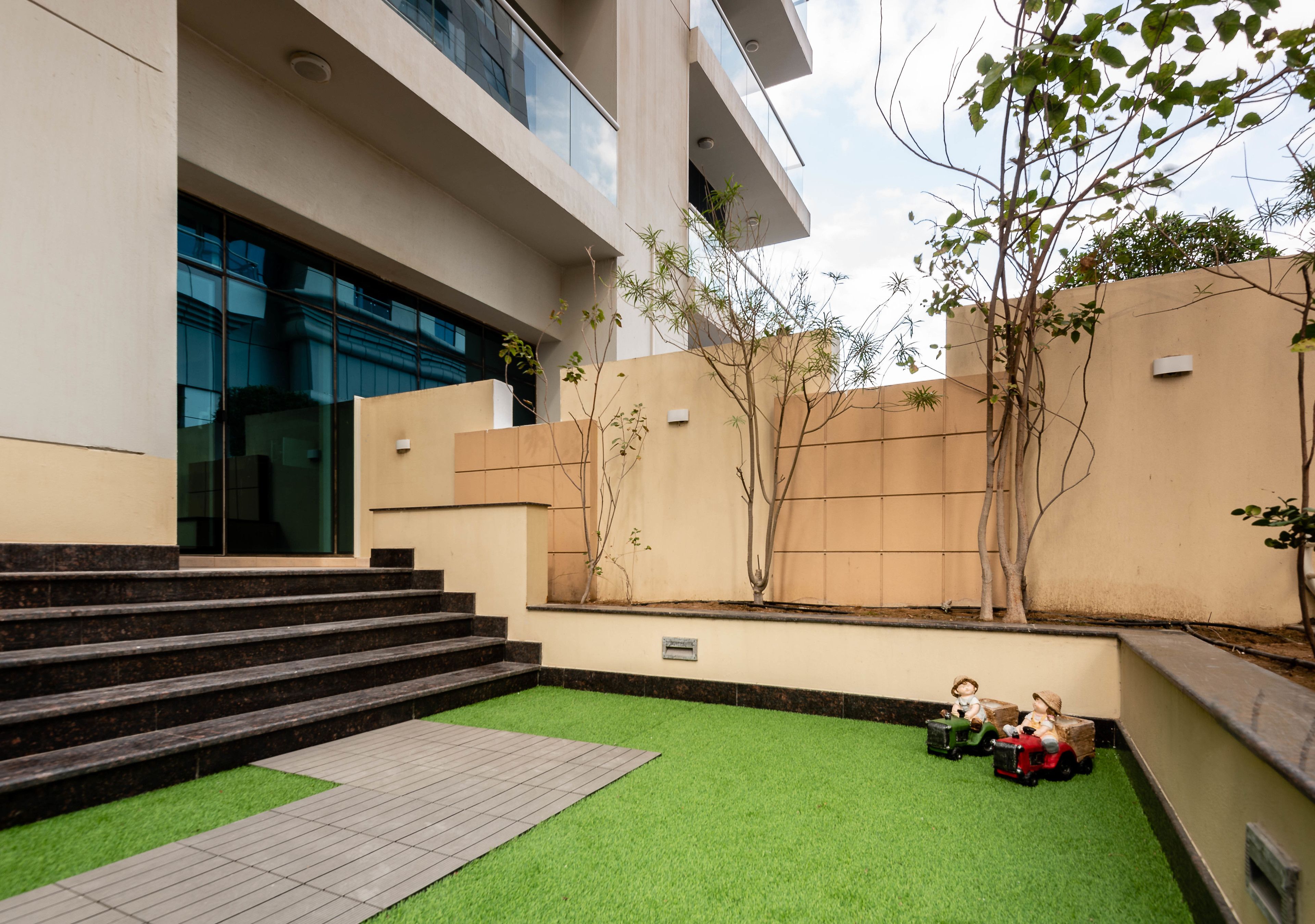 A modern building with a flat roof, large windows, and a paved area with artificial grass.