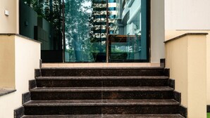 A set of black stone steps leading up to a glass door, with a small grassy area at the bottom. - Peaks Apartments Dubai Marina (Dubai)