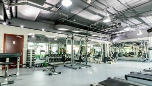 A gym with various exercise equipment, including weight machines and free weights, and a mirrored wall. - Peaks Apartments Dubai Marina (Dubai)