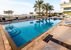 A rooftop swimming pool with lounge chairs and palm trees.