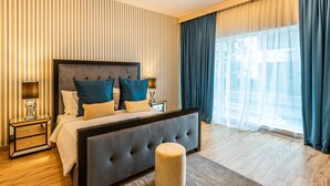 A modern hotel room with a large bed, a round ottoman, a nightstand, and a large window with curtains. - Peaks Apartments Dubai Marina (Dubai)