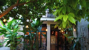 A courtyard with potted plants, a wooden deck, and a building entrance with glass doors. - Casa Sur Antalya (Antalya)