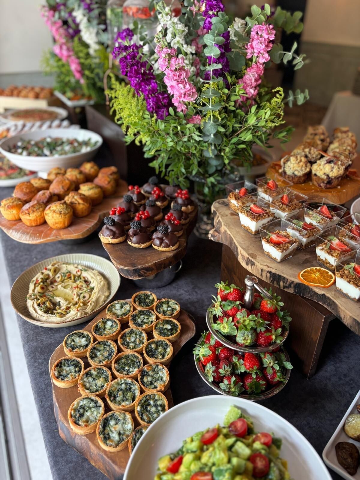 A buffet with various dishes including quiches, chocolate-covered treats, and a salad.