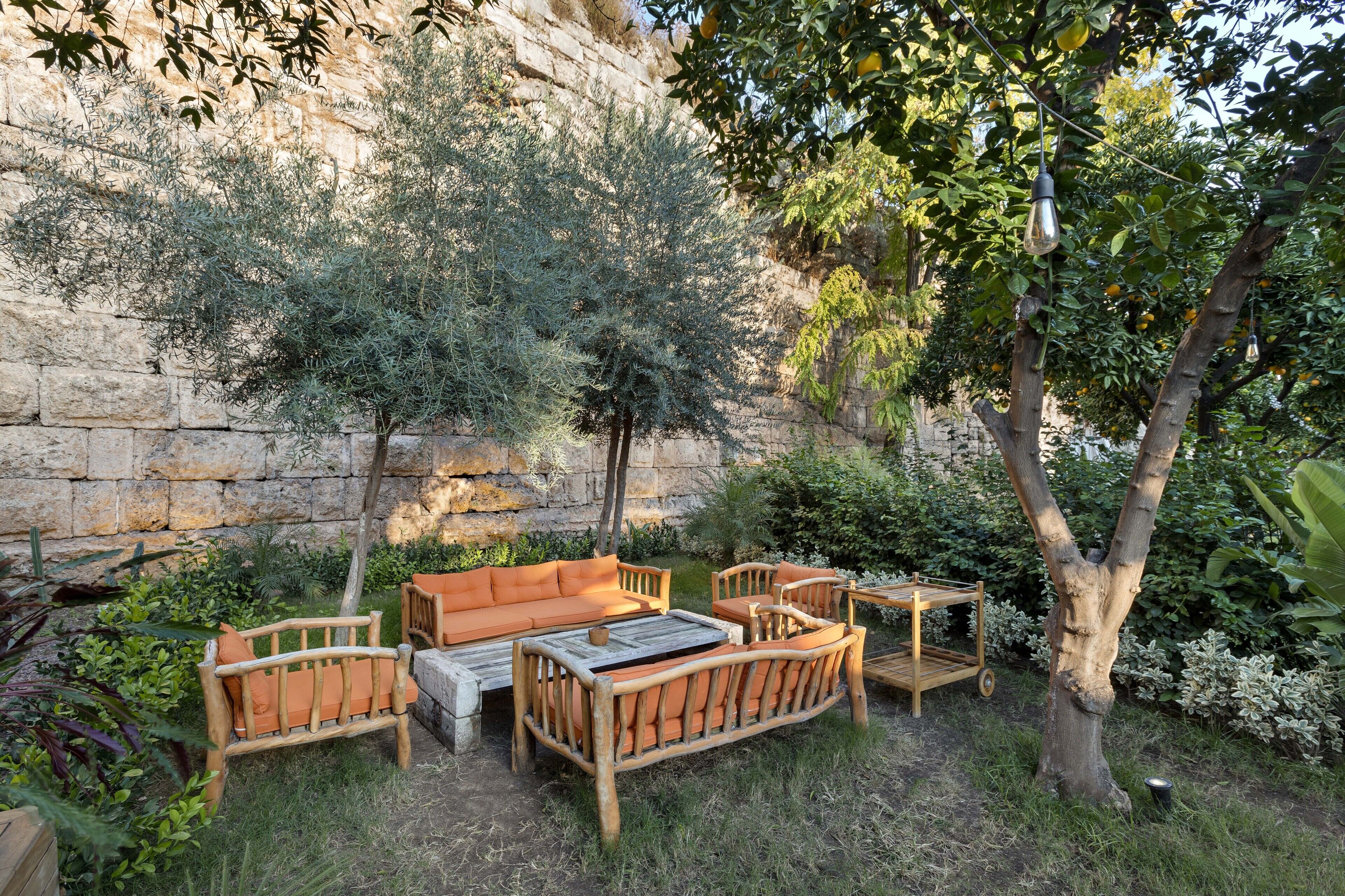 An outdoor seating area with wooden furniture and a stone wall backdrop.