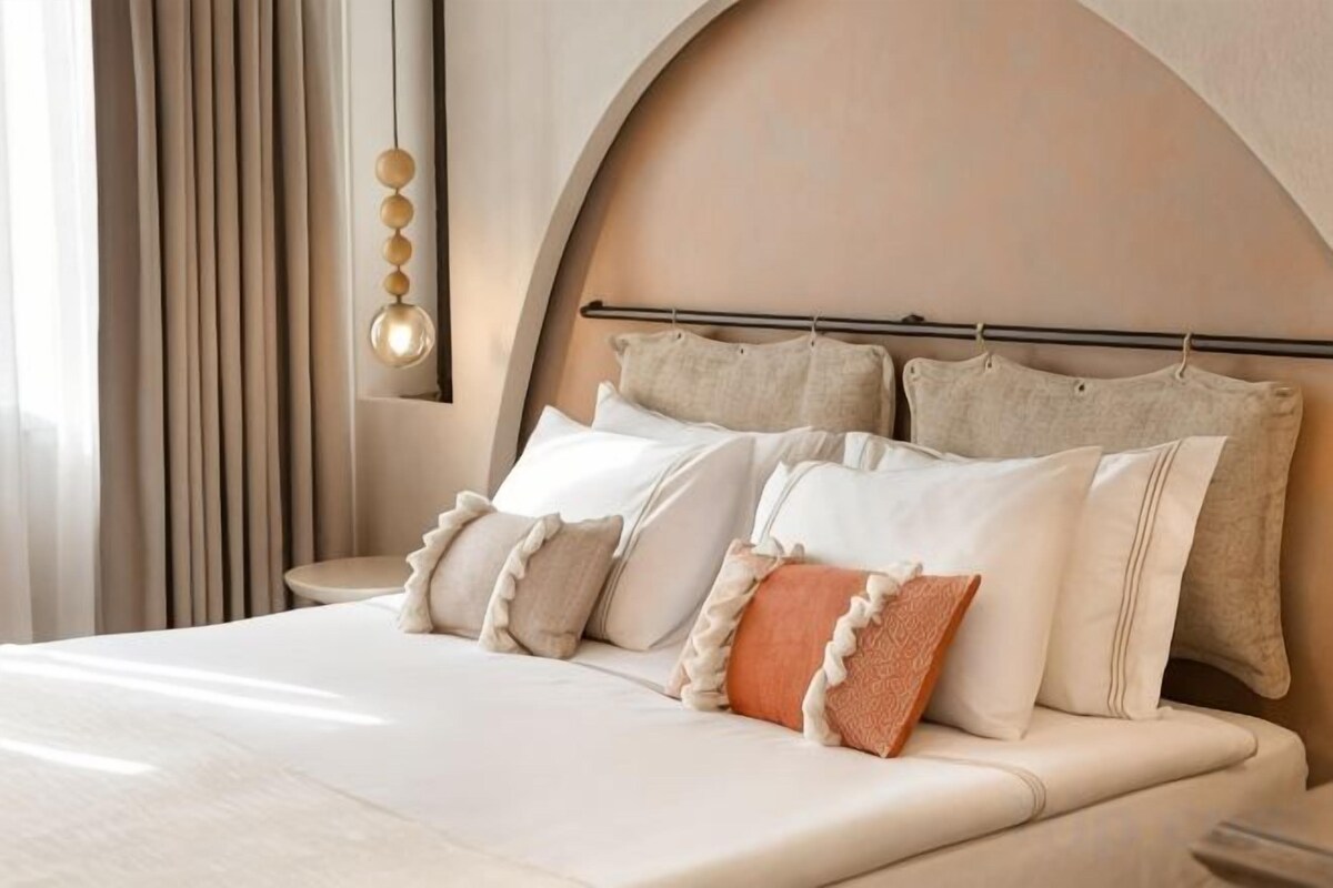 Una cama con cabecera, almohadas y una mesita de noche.