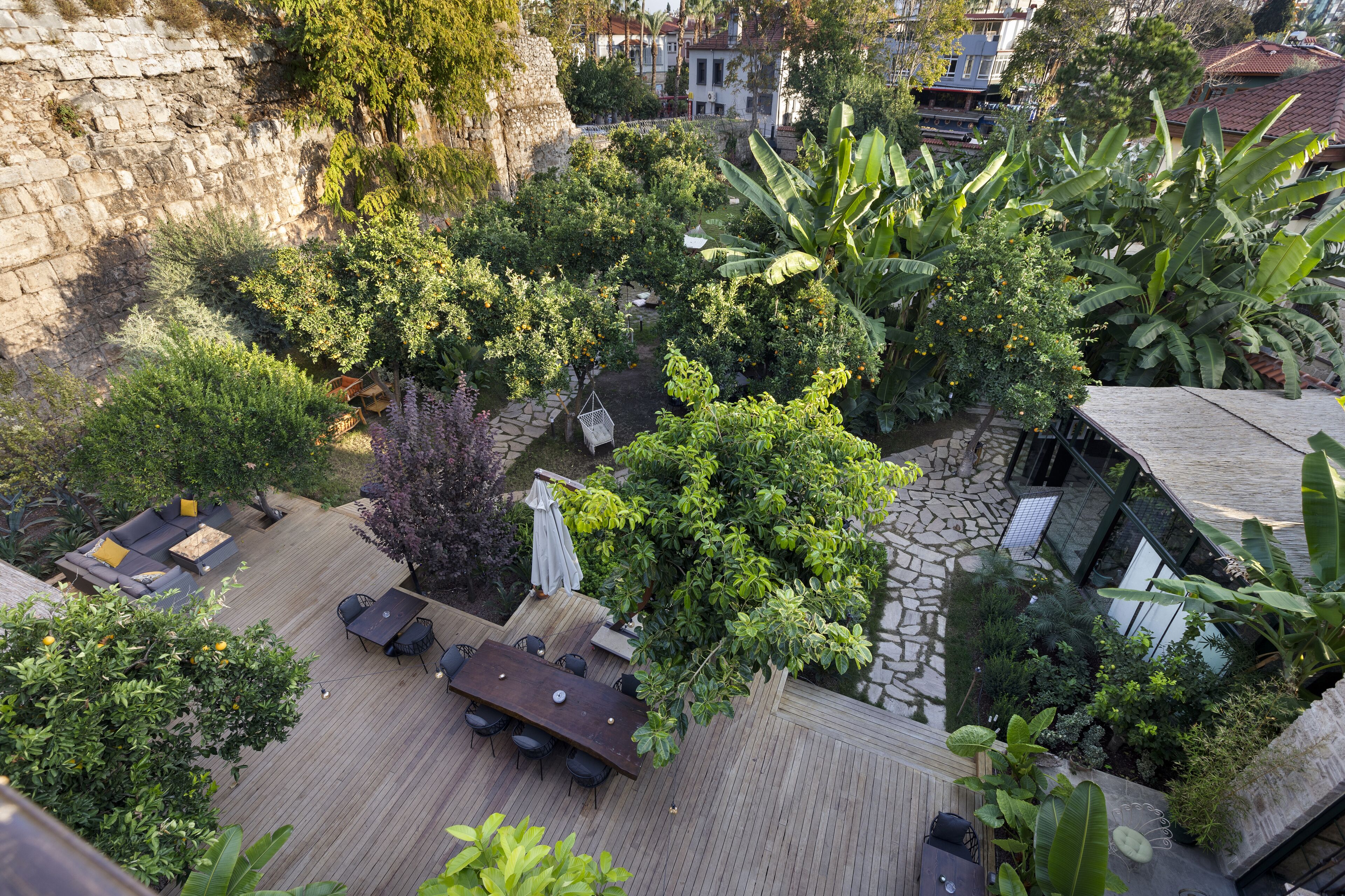 A rooftop garden with a wooden deck, outdoor seating, and lush greenery.