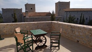 Une terrasse avec des murs en pierre, une table et des chaises.