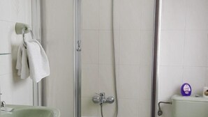Une salle de bain avec une douche à parois de verre, un lavabo vert et des toilettes.