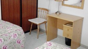 Une chambre avec deux lits, un bureau en bois, une chaise, une télévision et un miroir.