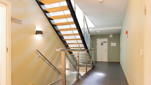 Un pasillo con una escalera de vidrio y metal que conduce a una plataforma. Un cartel en la pared indica 