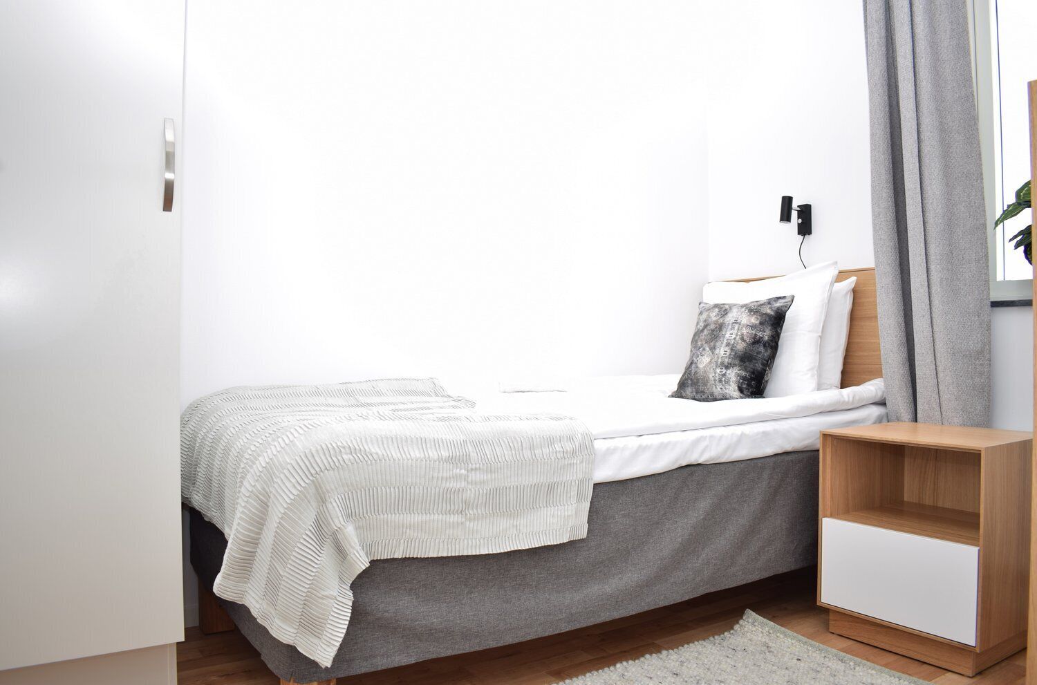 A minimalist bedroom with a bed, bedside table, and a nightstand.