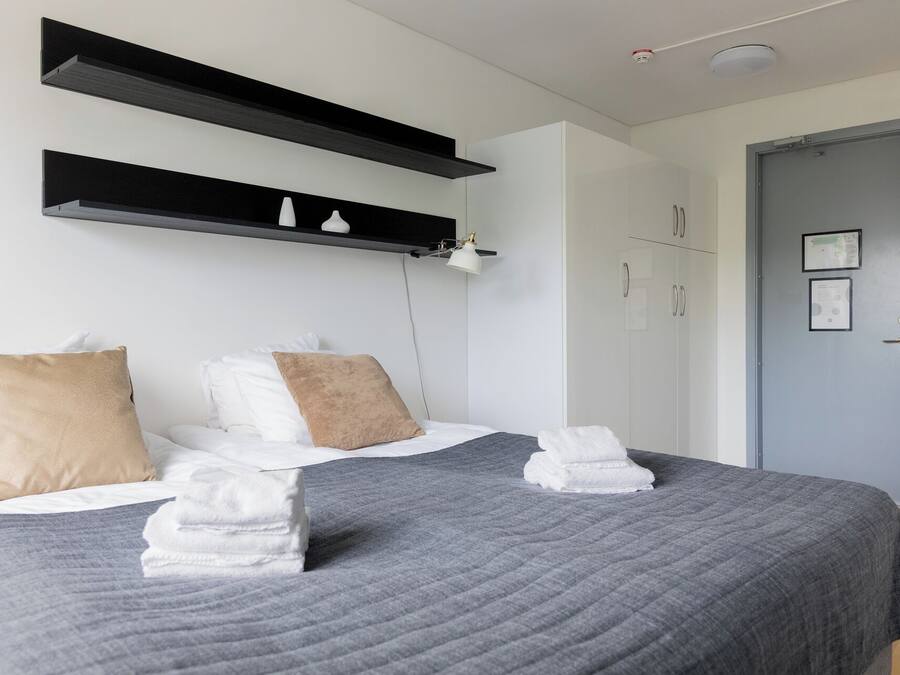 A modern bedroom with a bed, two bedside tables, a wardrobe, and a door.