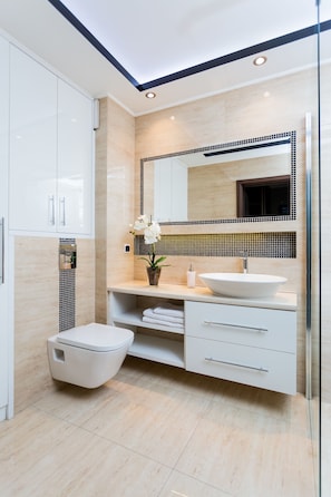 Een moderne badkamer met een wit toilet, een grote wastafel en een spiegel erboven.