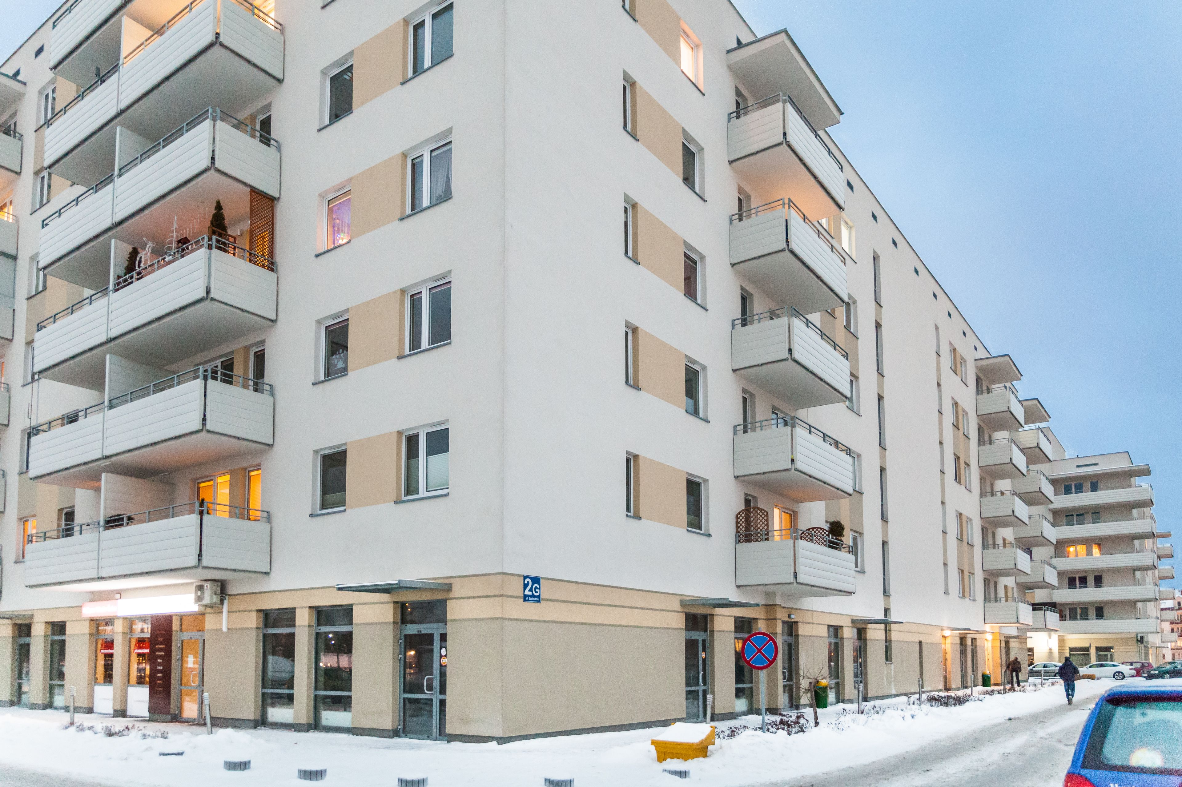 A multi-story hotel with balconies, a ground-level entrance, and a visible parking sign.