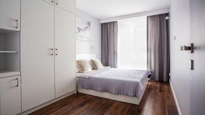 Quarto moderno com cama, guarda-roupa e janela com cortinas.