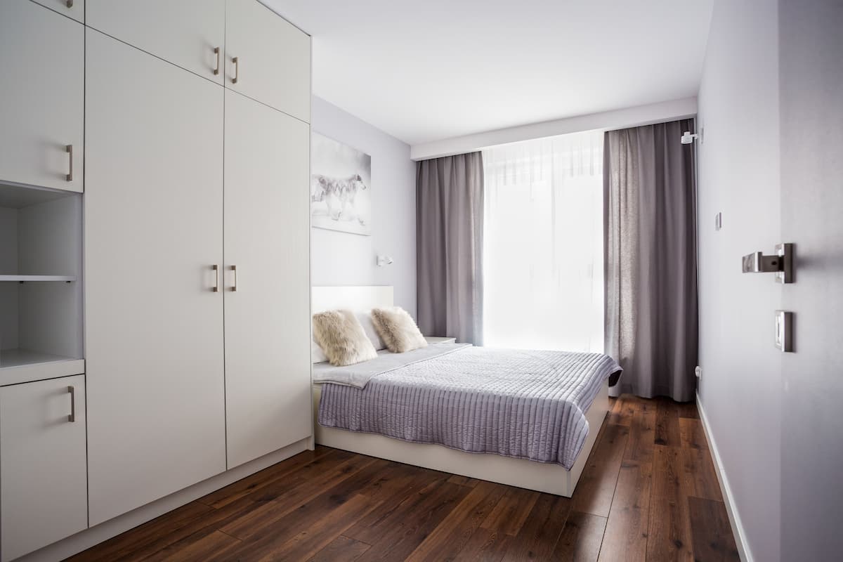 A modern bedroom with a bed, wardrobe, and a window with curtains.