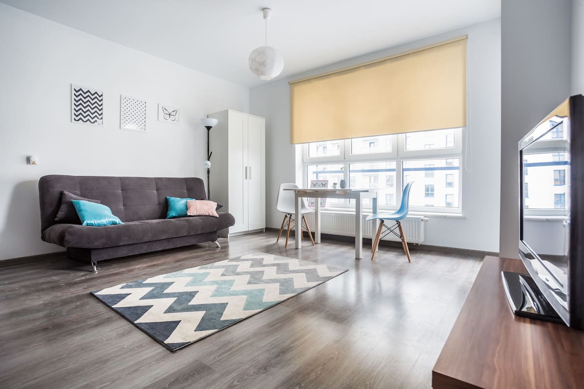 A modern living room with a sofa, a dining table, and a TV.