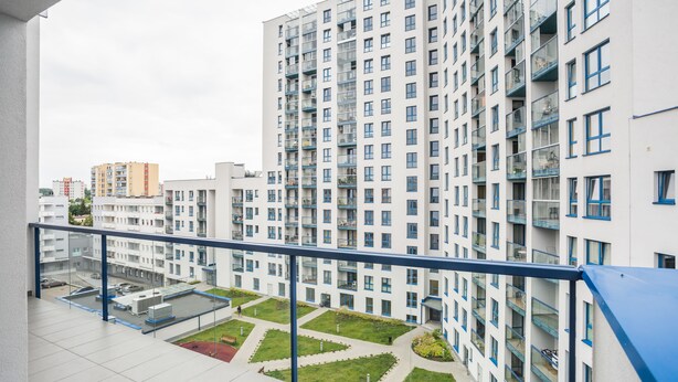 Um edifício residencial alto com várias varandas, um jardim no terraço e uma vista clara da área urbana ao redor.