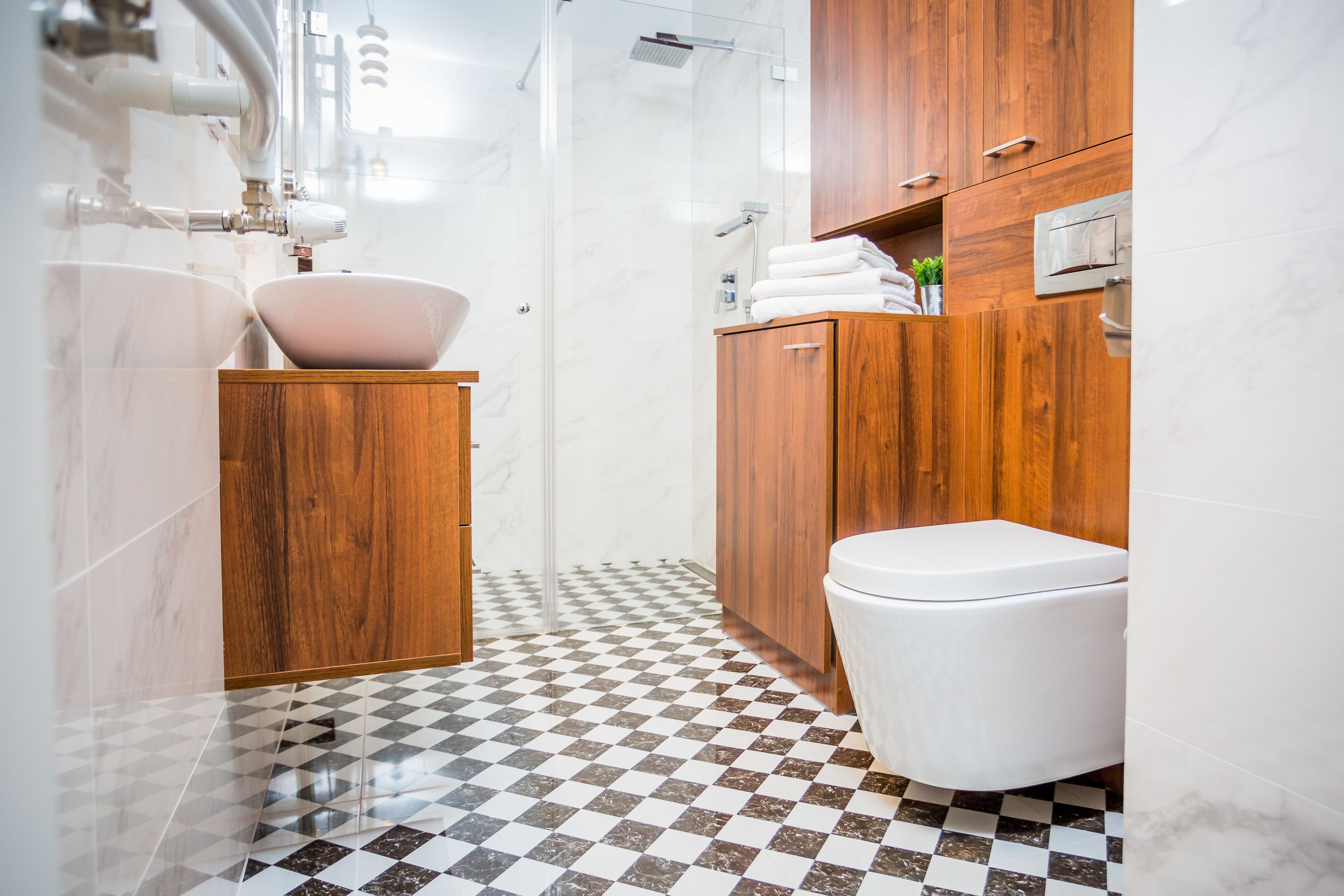 Une salle de bain avec un carrelage à motifs géométriques, un meuble-lavabo en bois, un lavabo blanc et des toilettes.