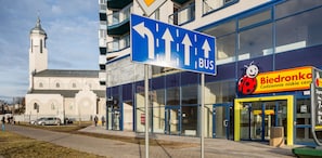 Ein Gebäude mit einem blauen Schild, das eine Bushaltestelle anzeigt, und ein Geschäft mit einem Marienkäfer-Logo.