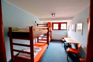A dormitory room with bunk beds, a small table, chairs, and a radiator. - Herberge Orange - Hostel (Meissen)