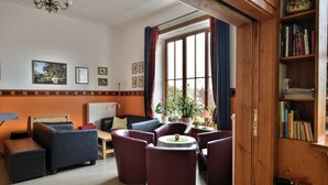 Een gezellige woonkamer met een open haard, comfortabele zithoeken, een boekenkast en uitzicht door grote ramen.