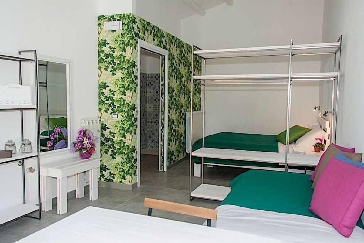 A room with bunk beds, a small desk, and a mirror.