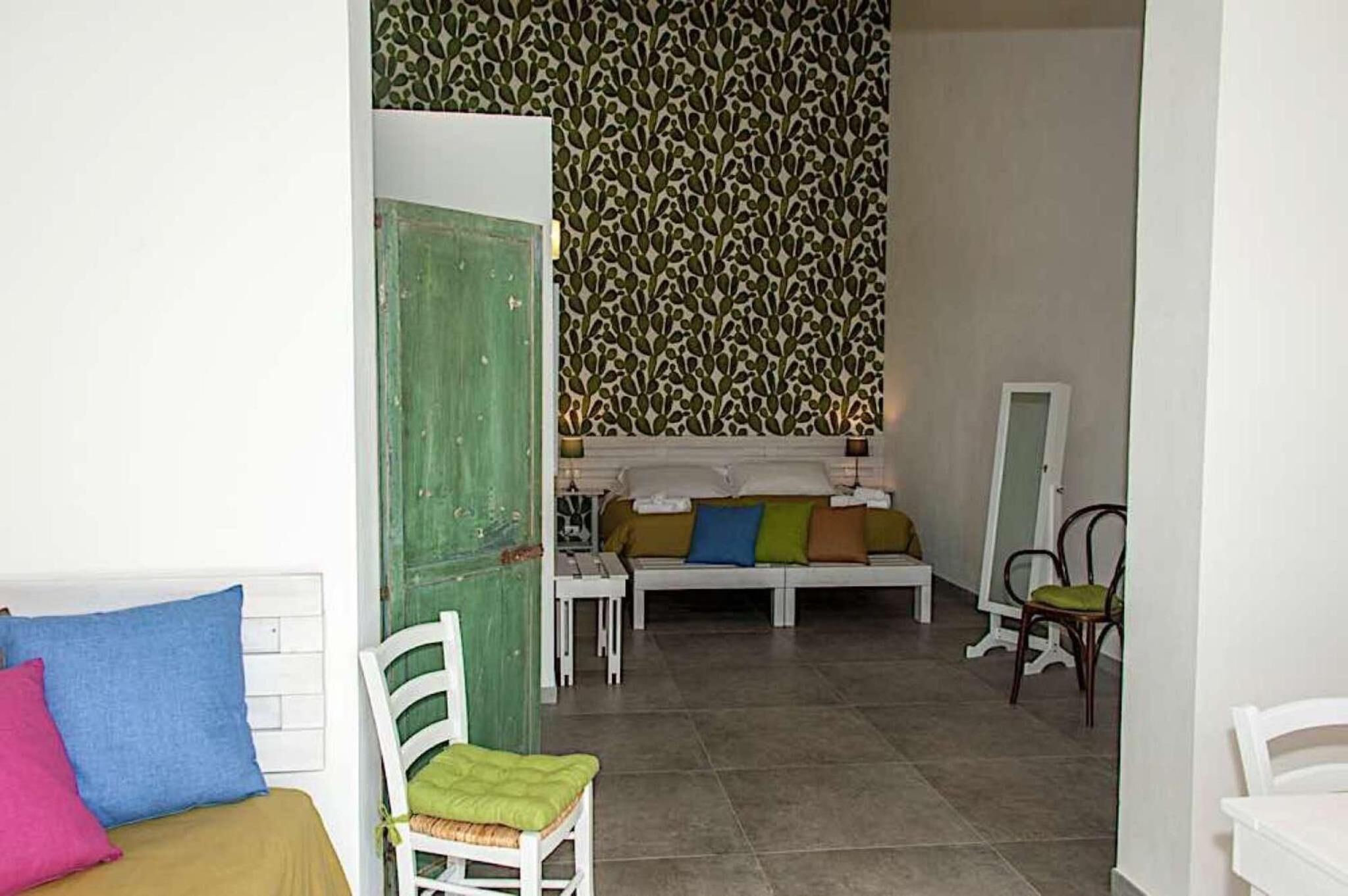 A room with a bed, a chair, a sofa, and a mirror.