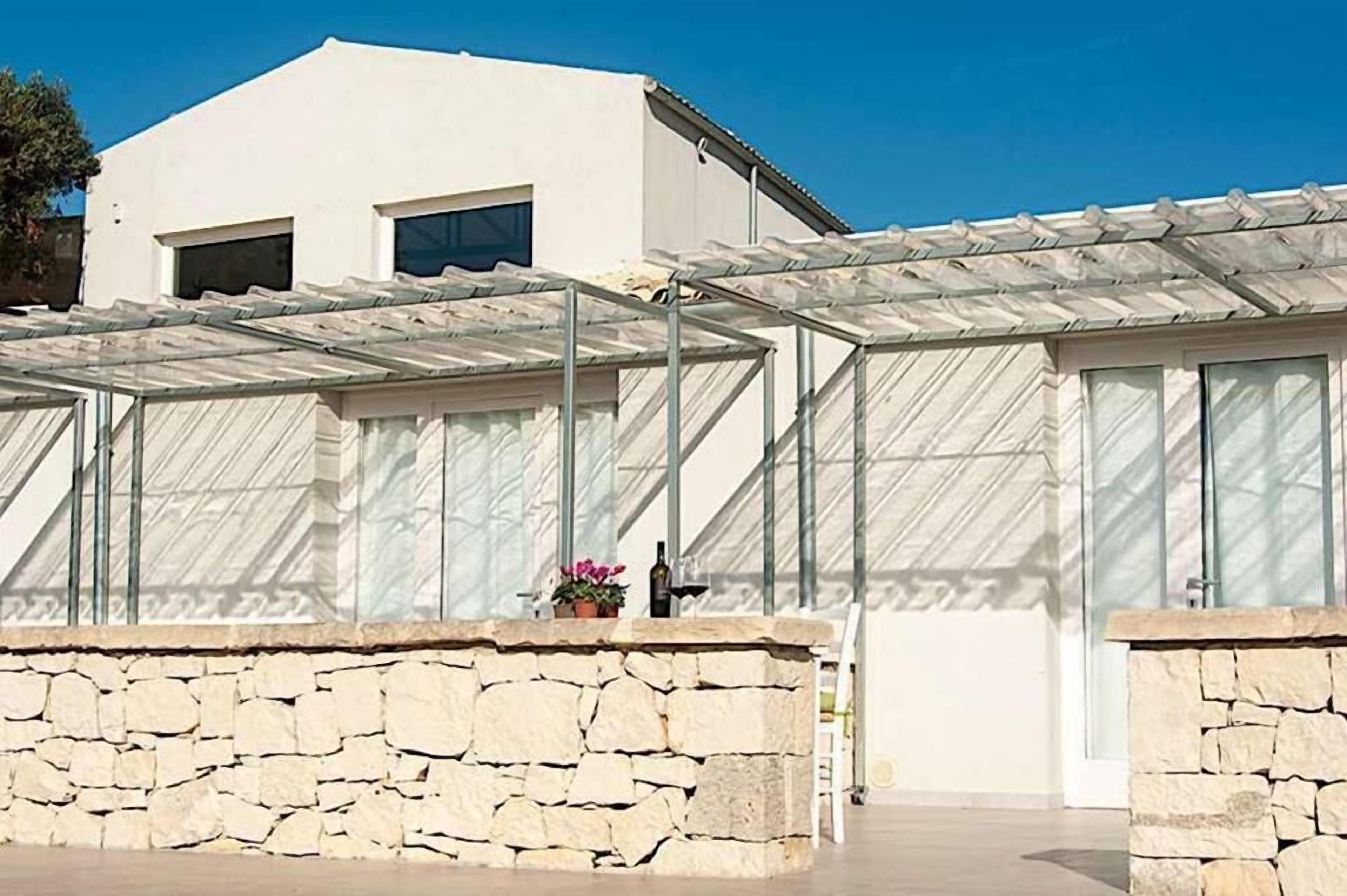 Ein modernes Gebäude mit einer Steinwand und einem überdachten Außenbereich mit Metallkonstruktion.
