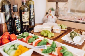 A table with various cheeses, grapes, and a chicken sculpture. - Das Appartmenthaus Silvia (Bad Fuessing)