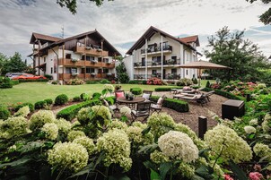 Un hotel con varios balcones, un jardín de hortensias y mobiliario exterior.