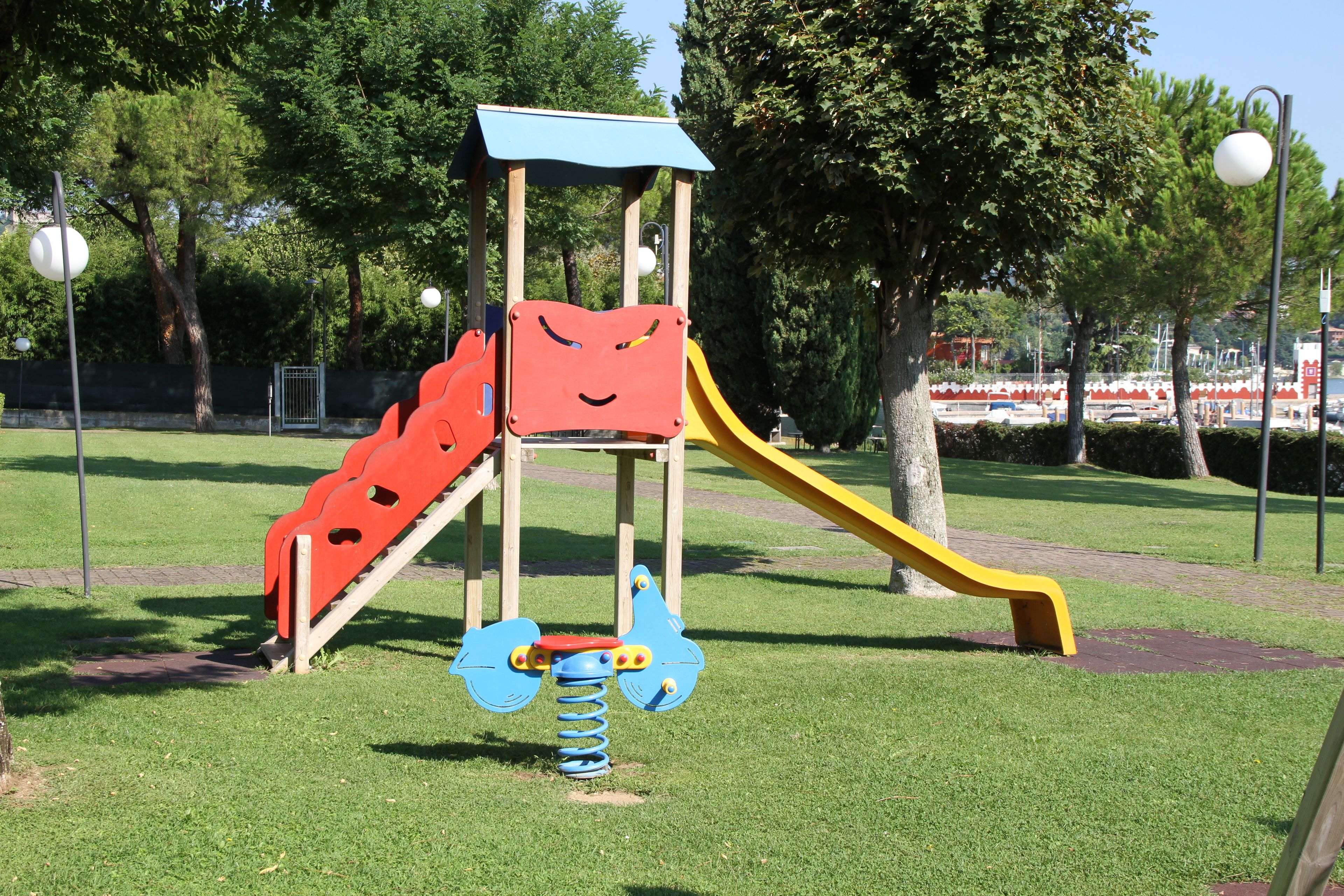 A playground with a slide, a climbing structure, and a spring-mounted toy.