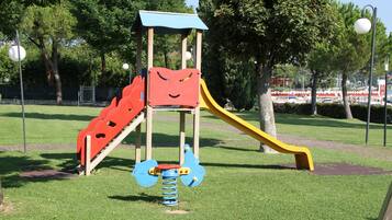 A playground with a slide, a climbing structure, and a spring-mounted toy.