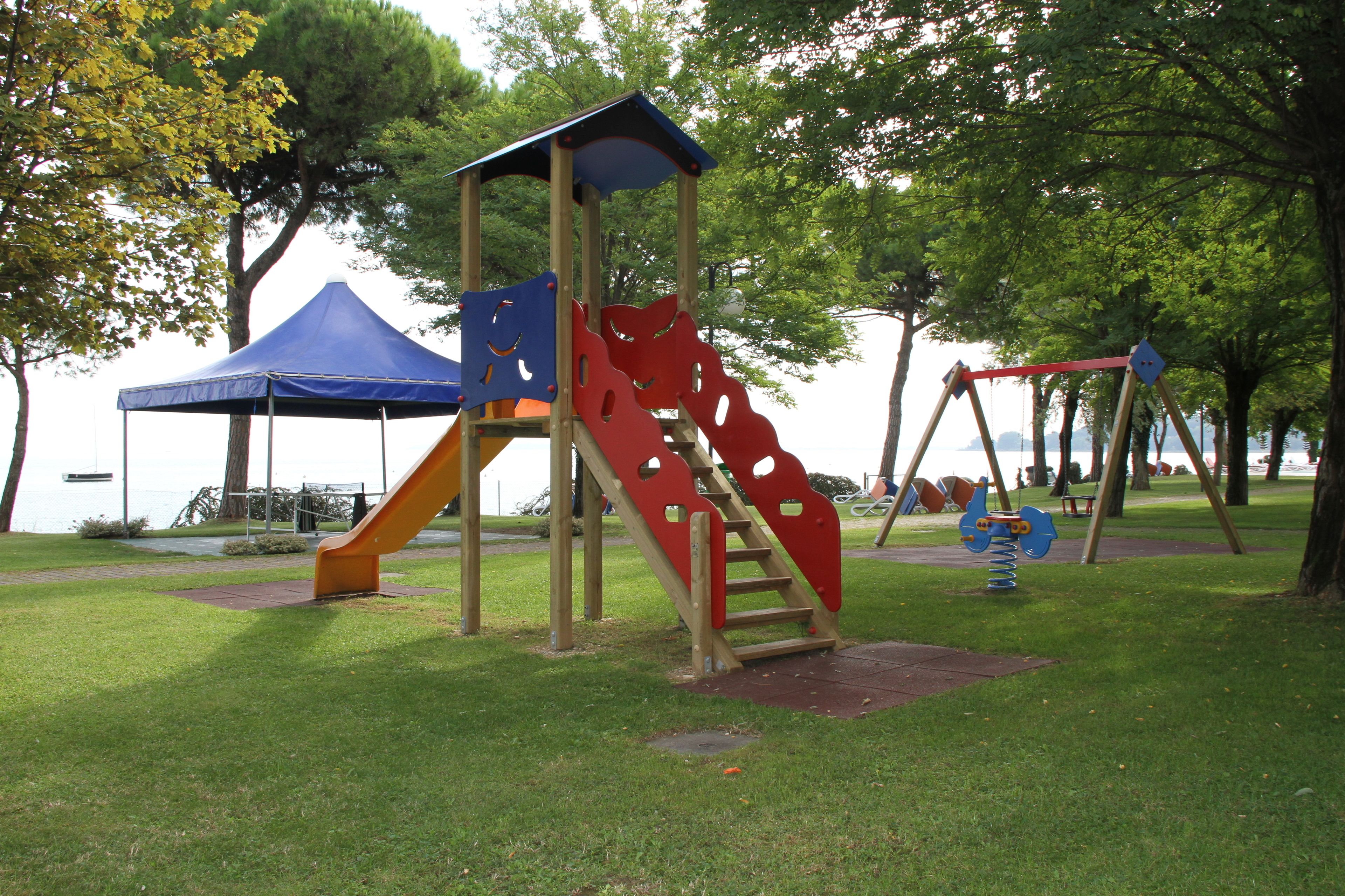 Un parque infantil con tobogán, estructura para escalar y columpios.