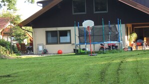 A house with a well-maintained lawn, a basketball hoop, and a trampoline. - Ferienwohnung Schwahn (Herdwangen Schoenach)