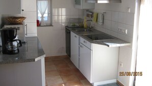 A compact kitchen with white cabinets, a stainless steel sink, and a coffee maker. - Ferienwohnung Schwahn (Herdwangen Schoenach)