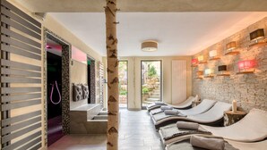 A spa area with reclining chairs, a birch tree, and a brick wall with wall-mounted lights. - Parkhotel Emstaler Höhe (Bad Emstal)