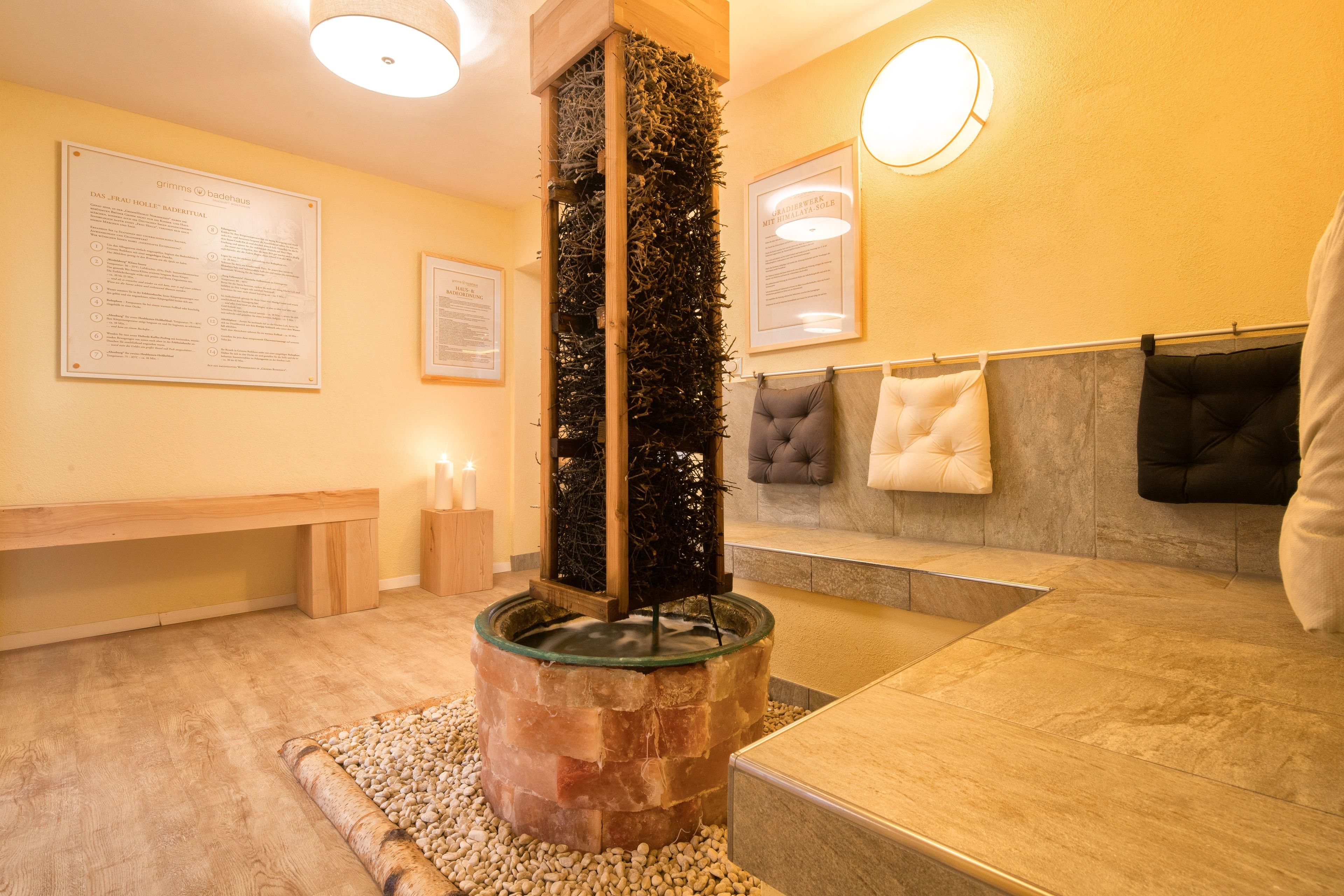 A spa area with a wooden bench, a water feature, and a seating area with cushions.