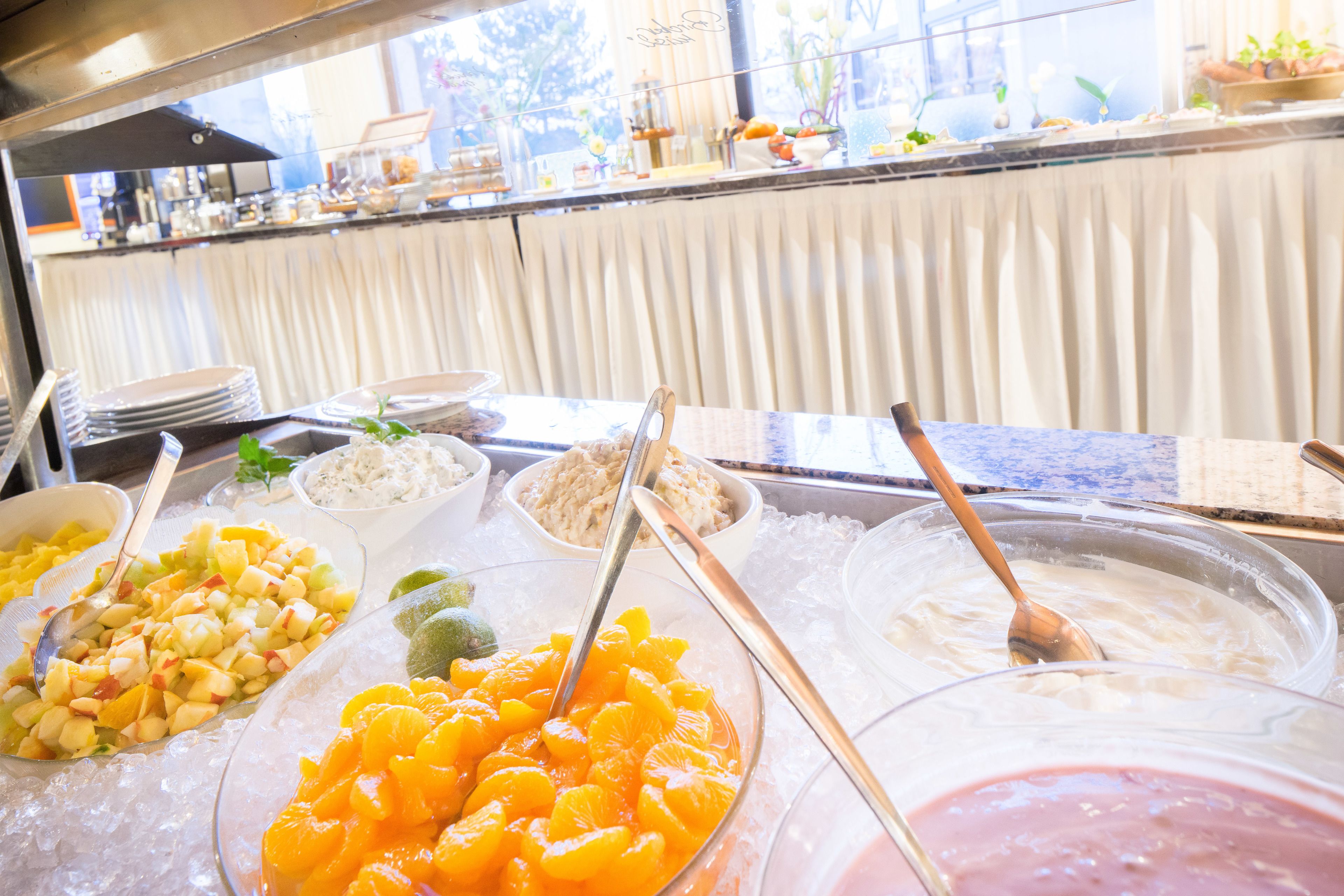 Un bufé con diversas opciones de comida, incluyendo frutas y postres.