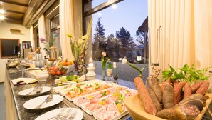 A buffet with various food items, including meats, cheeses, and fruits, arranged on a marble countertop. - Parkhotel Emstaler Höhe (Bad Emstal)
