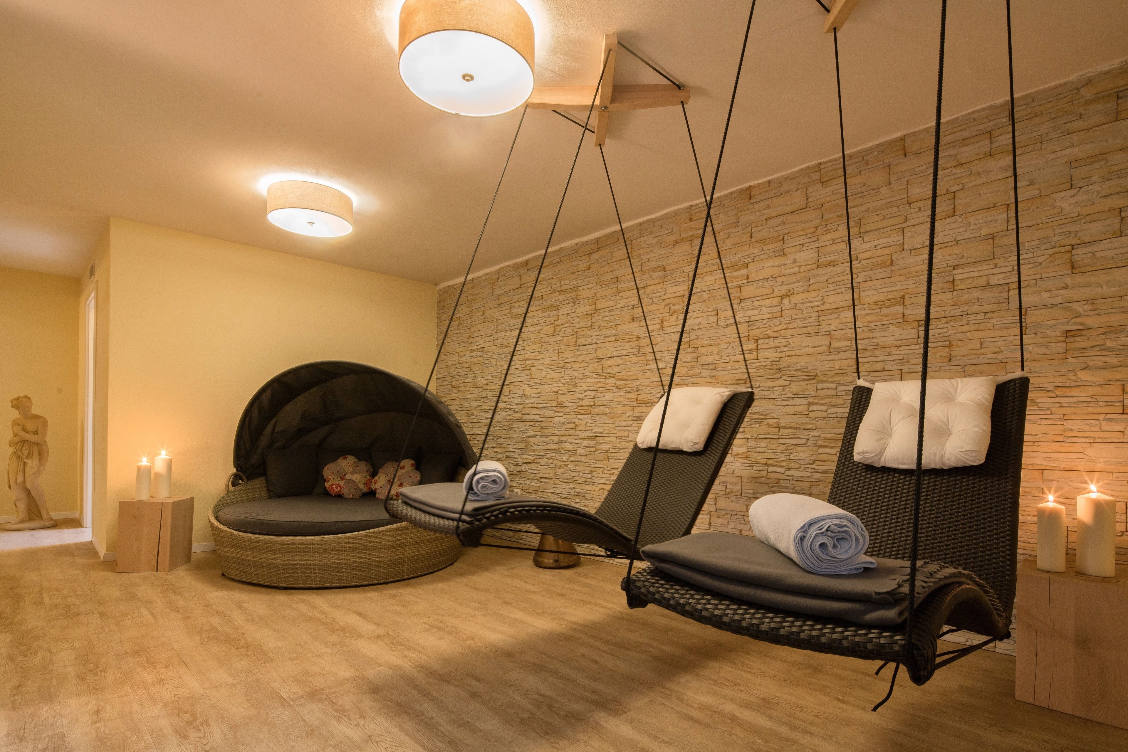 Habitació d'spa amb dues cadires penjants, una paret de pedra i espelmes.