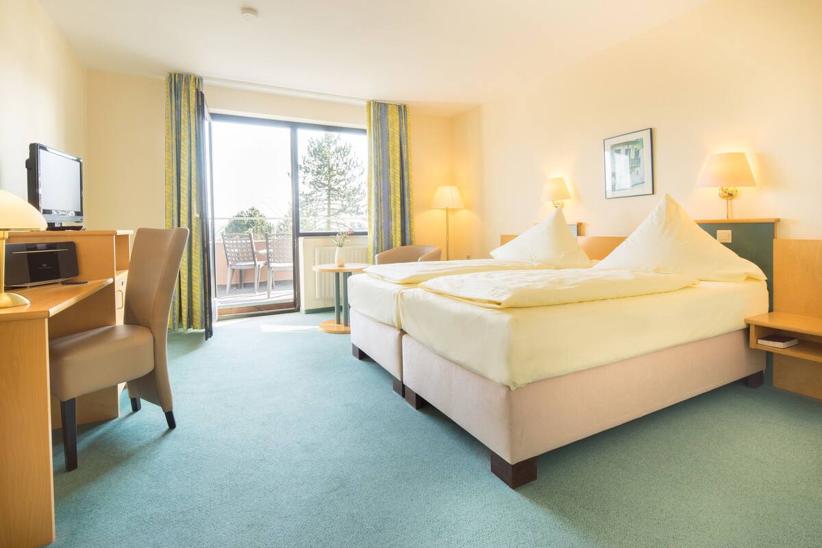 A hotel room with a bed, desk, chair, and a television.