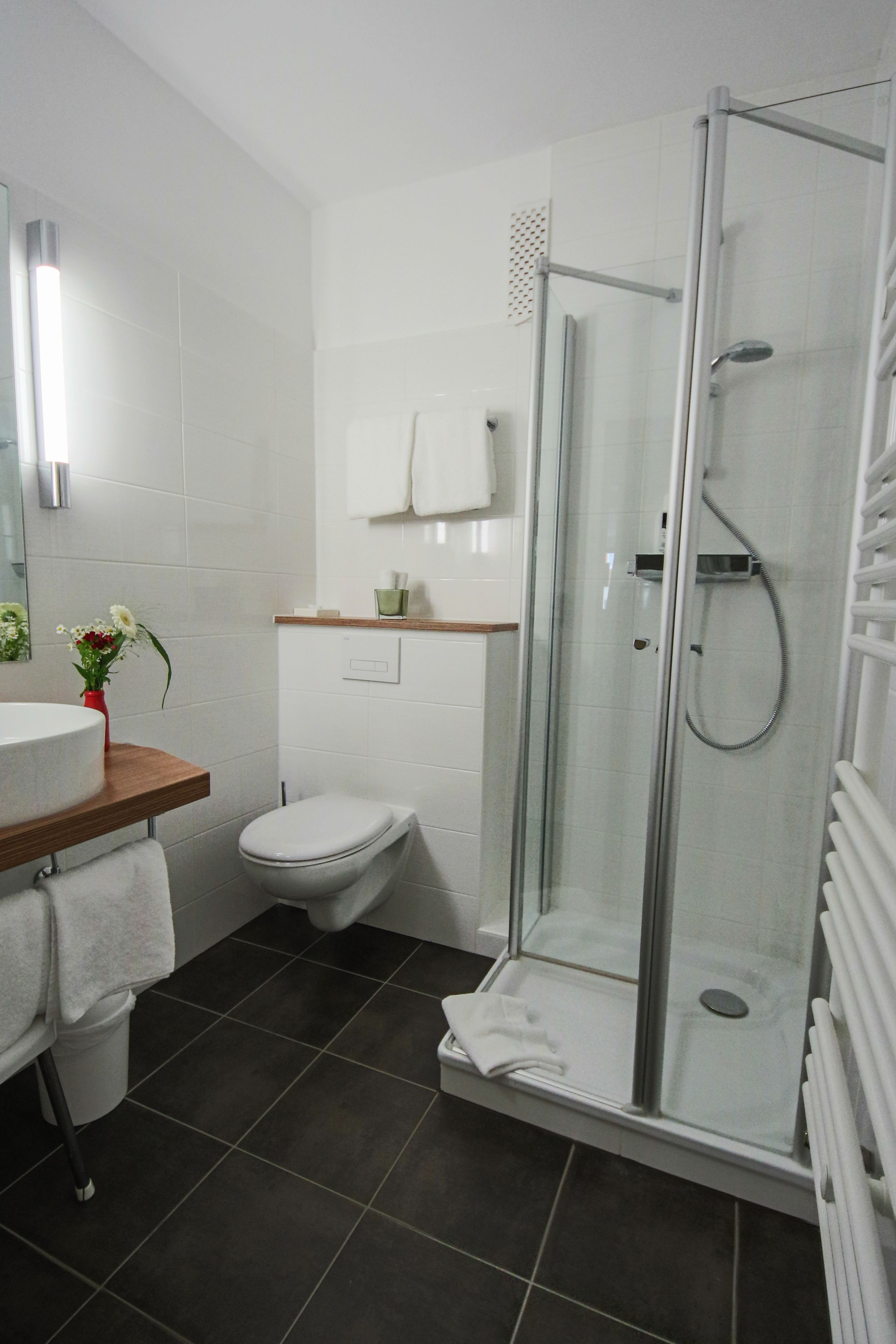 Ein modernes Badezimmer mit einer gläsernen Duschkabine, einer weißen Toilette und einem Holzwaschtisch.