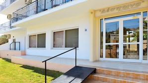 A two-story building with a balcony, a staircase leading to the entrance, and a sign above the door. - Despoina (Skiathos)