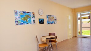 A room with a dining table and chairs, a wall clock, and three maps. - Despoina (Skiathos)