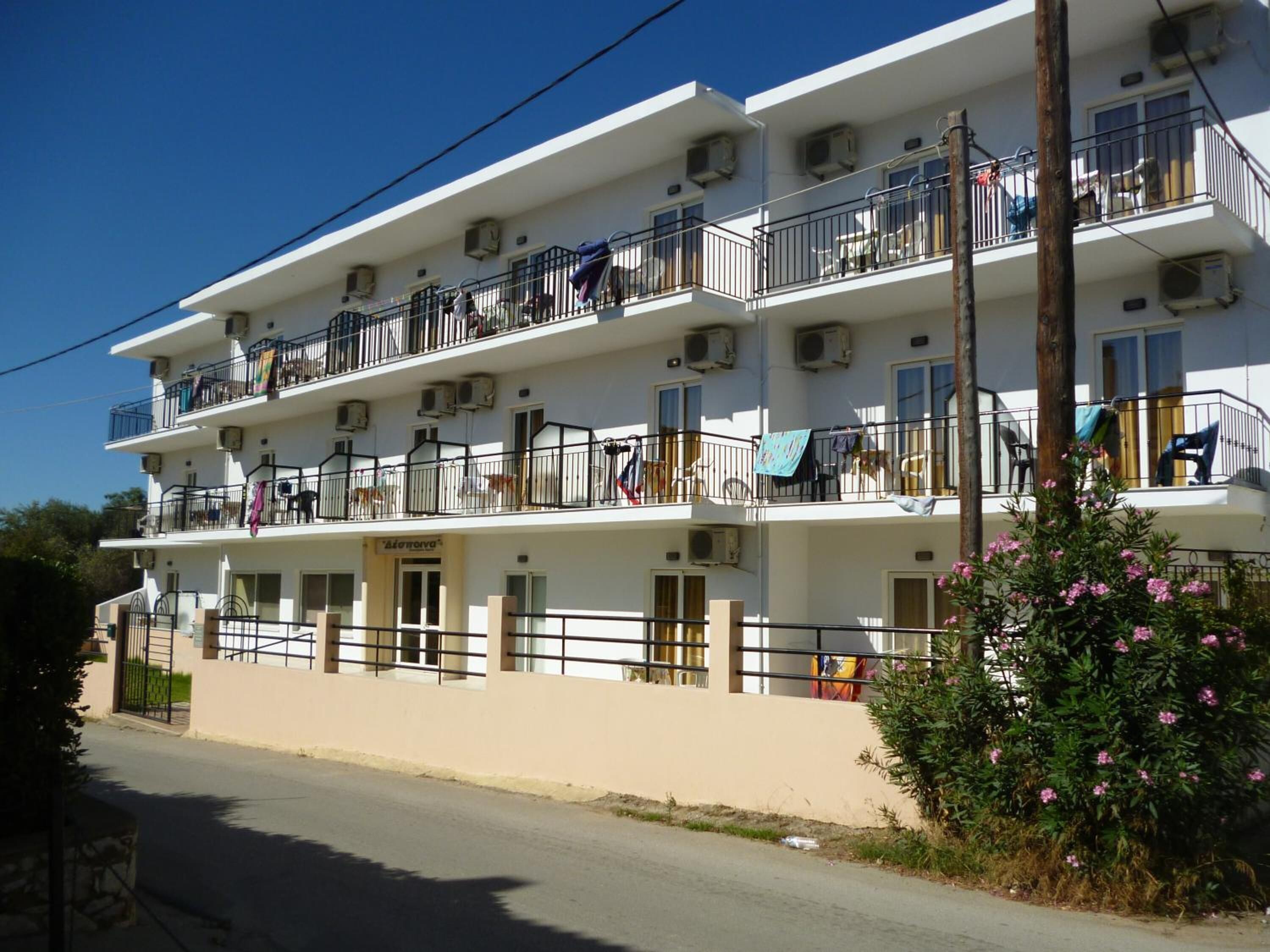 A multi-story hotel with balconies, air conditioning units, and a street view.
